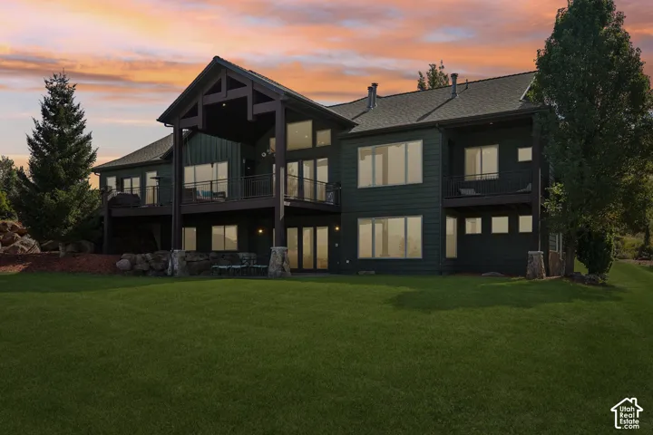 Multi-level exterior with dark green siding, multiple balconies with dark railings, a prominent covered porch, and extensive fenestration