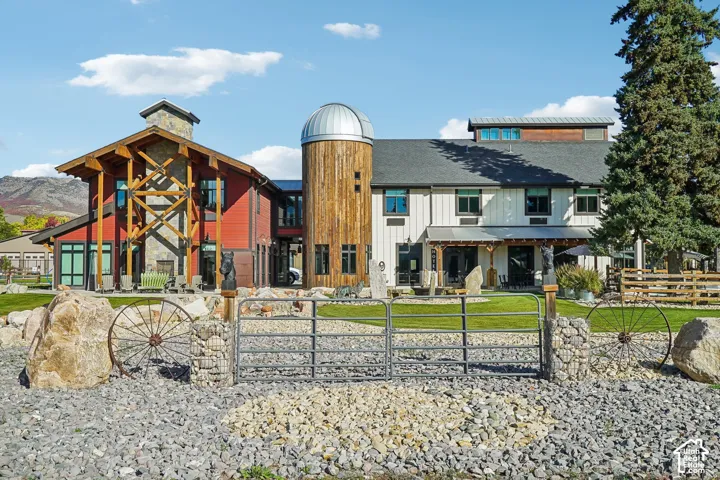 Red and white multi-level exterior with a wood-clad tower and dome, a stone chimney, exposed timber framing, and a large covered patio