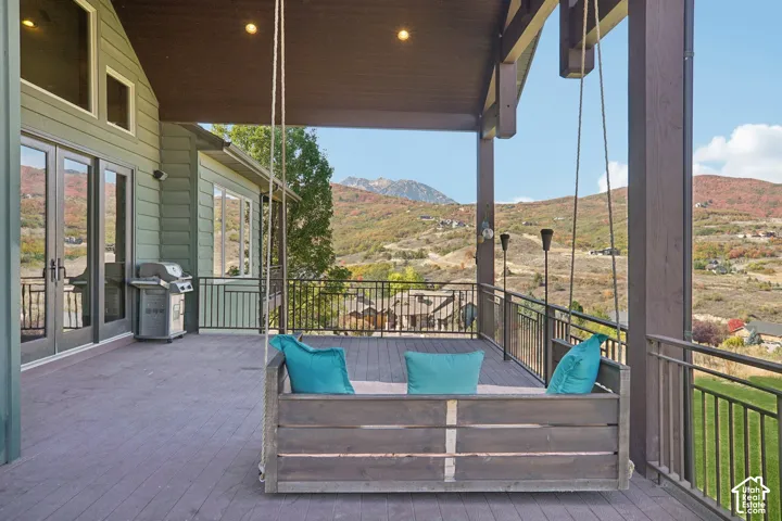 Covered deck featuring a composite surface, metal railing, and a mountain backdrop