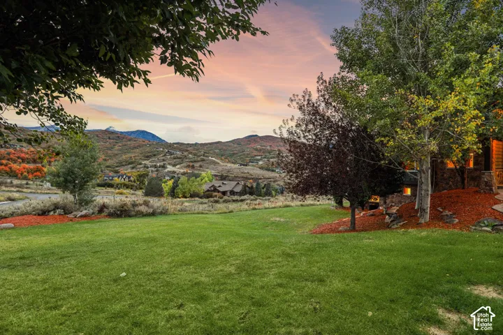 Expansive lawn with mature trees, surrounded by mountainous terrain