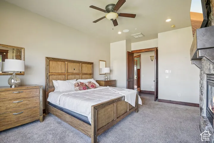 Stone fireplace with a wood mantel, ceiling fan, recessed lighting, and wood-paneled doors