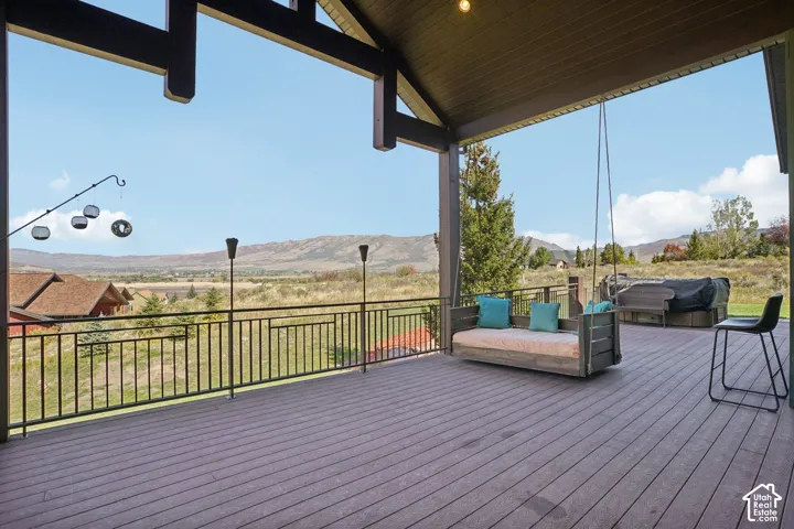 Expansive covered porch featuring a composite deck, exposed wood beams, and a metal railing