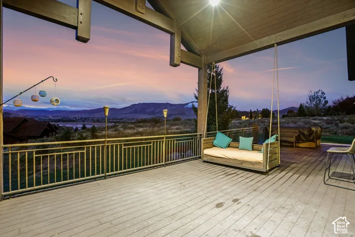 Expansive covered deck featuring wood-finish flooring, exposed beam ceiling, and a metal railing