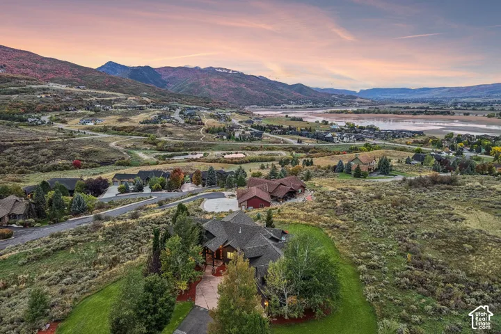 Expansive property featuring a multi-level residence with a gray shingle roof, mature landscaping, and a paved driveway