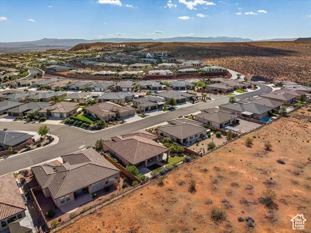 Aerial perspective featuring single-story residential structures with tile roofing, paved streets, and expansive arid landscape backdrop