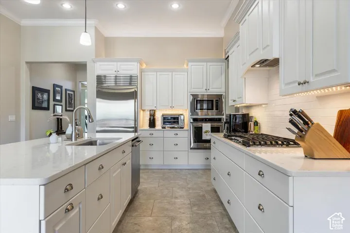 Kitchen featuring white shaker-style cabinetry, a stone-composite island countertop, stainless steel built-in appliances, a gas cooktop, and tile flooring