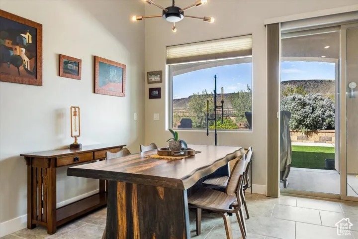 Multi-light sputnik chandelier, tile flooring, large window with pleated shade, and sliding glass door with desert landscape backdrop