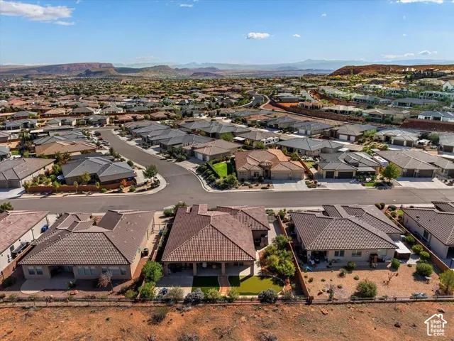 Aerial perspective of a residence featuring a covered rear patio, low-maintenance desert landscaping, and prominent mountain horizon