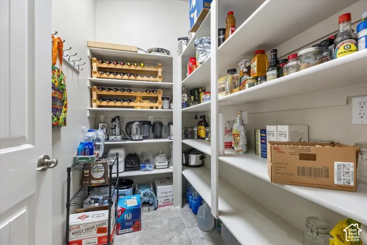 Walk-in pantry featuring white custom built-in shelving and tile flooring