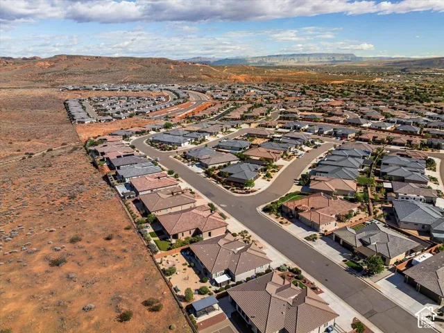 Aerial perspective of a residential community featuring paved streets, tile-roofed residences, and desert landscape with mountain backdrops