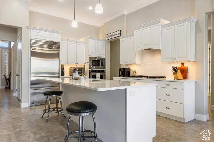 Kitchen featuring a large central island with quartz countertops, custom white cabinetry, stainless steel appliances, and tile flooring