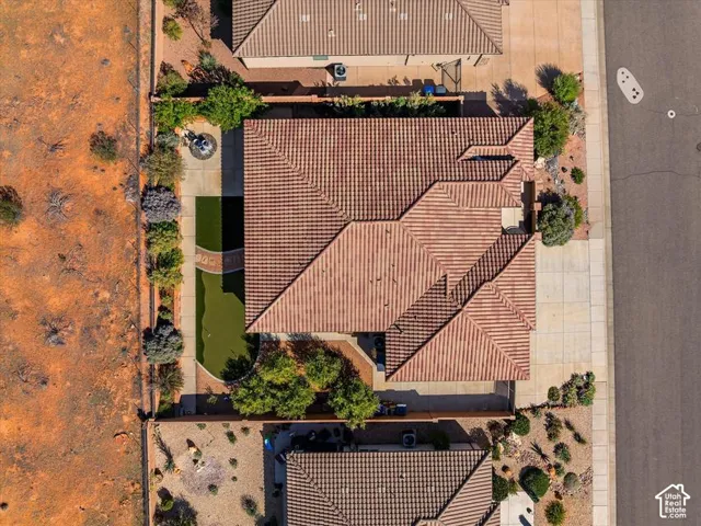 Aerial perspective featuring a tile roof, concrete driveway, and a backyard with a putting green and mature landscaping