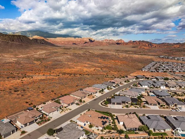 Aerial view of the residential community featuring desert landscape, mountain scenery, and solar panels installed on shingled rooflines