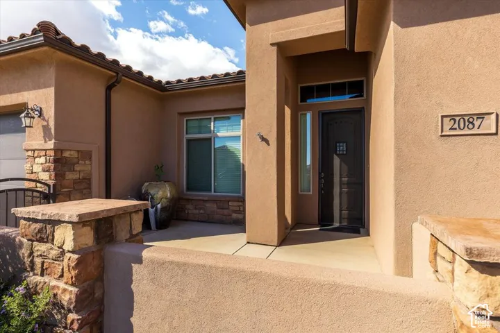 Stucco exterior featuring stacked stone accents, covered entryway, tile roof, and a wood-finish front door with a glass inlay