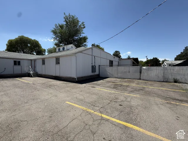 Paved parking area with marked stalls, metal exterior siding, and chain-link perimeter fencing