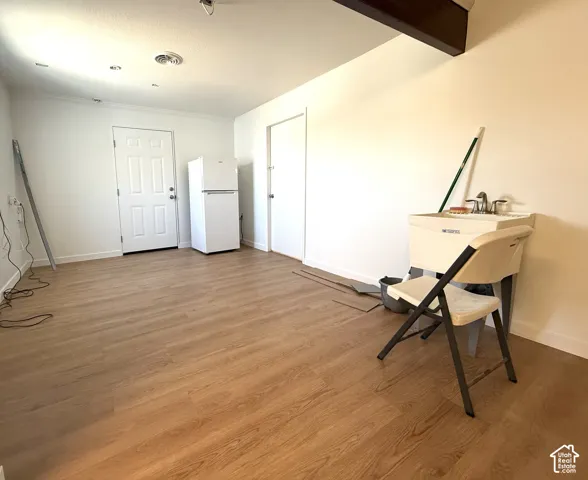 Room featuring wood-finish flooring, a utility sink with a dual-handle faucet, recessed ceiling lighting, and exposed structural beam detail