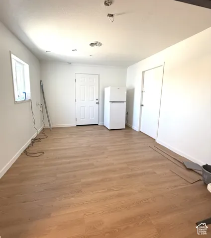 Interior space featuring wood-finish flooring, a six-panel exterior door, and a standard-size refrigerator