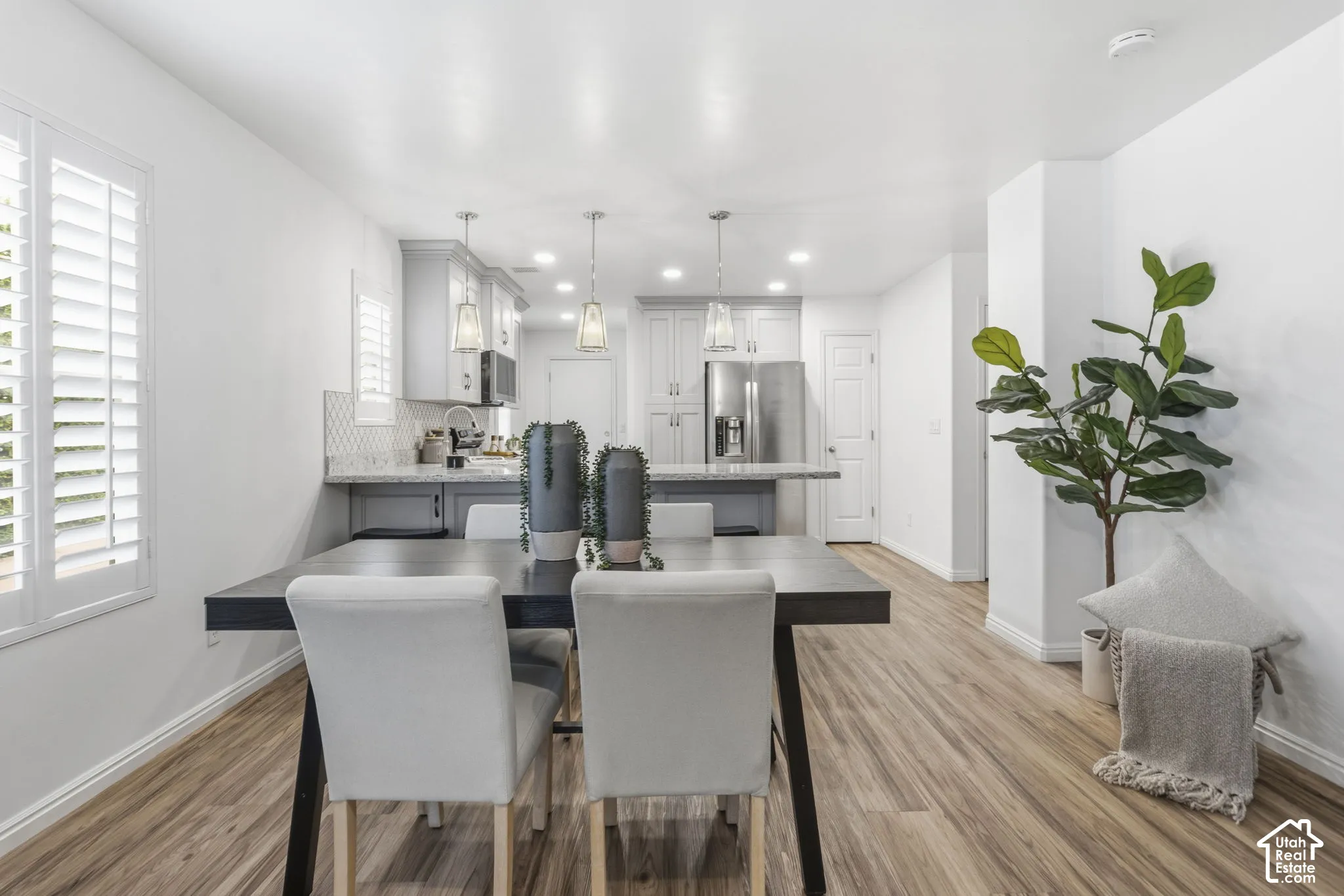 Kitchen featuring shaker-style cabinetry, stone-finish countertops, geometric tile backsplash, stainless steel appliances, and wood-finish flooring