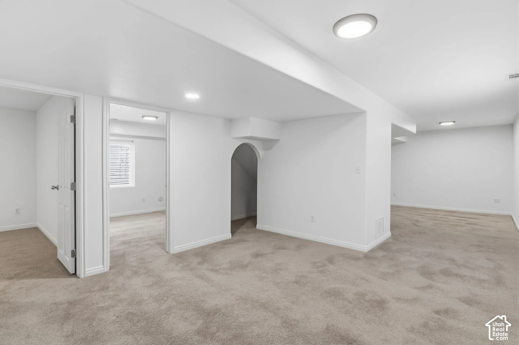 Neutral-toned carpeting, flush-mount lighting, and an arched architectural cutout featuring interior access