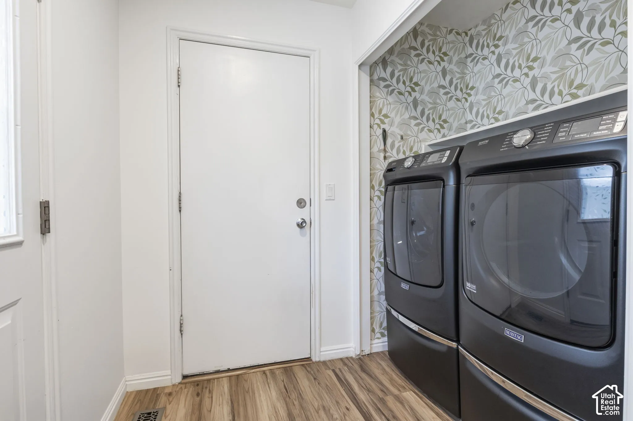 Laundry area featuring botanical-patterned wallpaper, built-in shelving, wood-finish flooring, and a dedicated exterior door