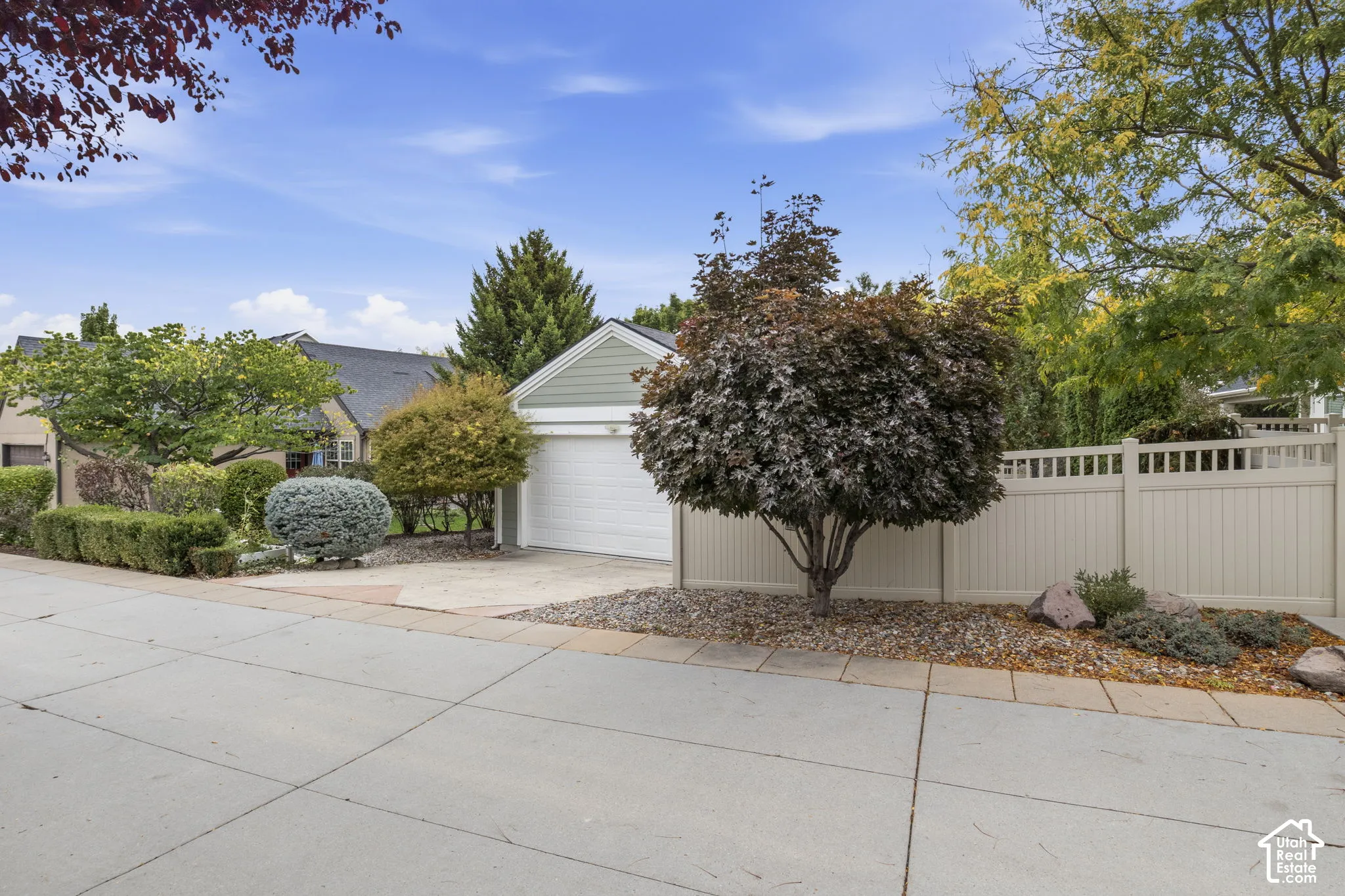 Detached garage featuring horizontal siding, a white roll-up door, concrete driveway, and surrounding privacy fencing