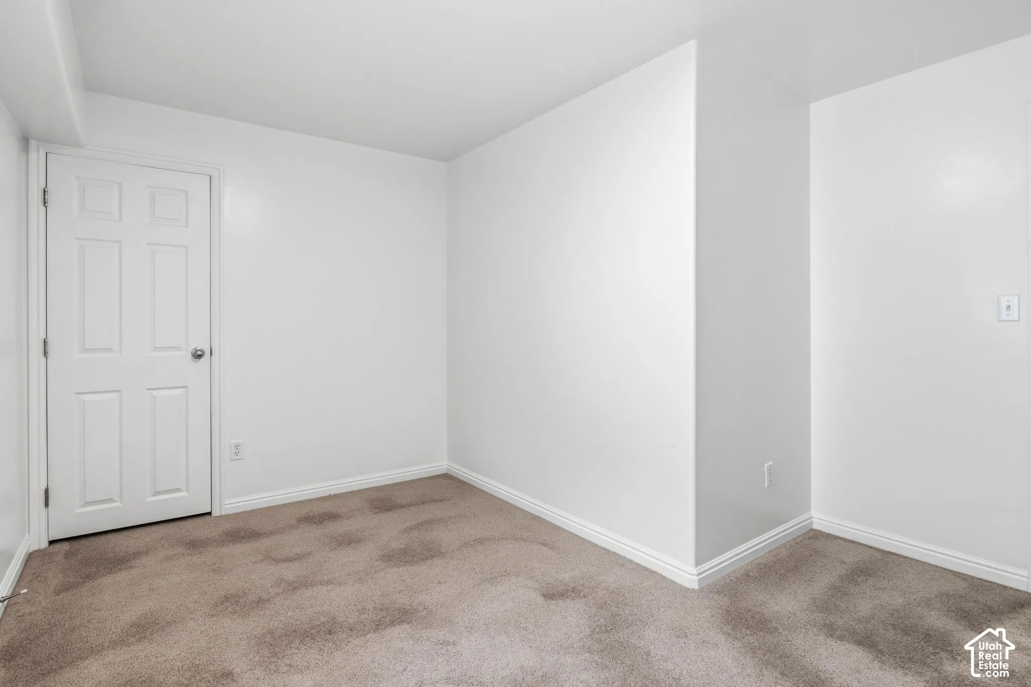 Interior space featuring neutral wall tones, wall-to-wall carpeting, and a four-panel interior door