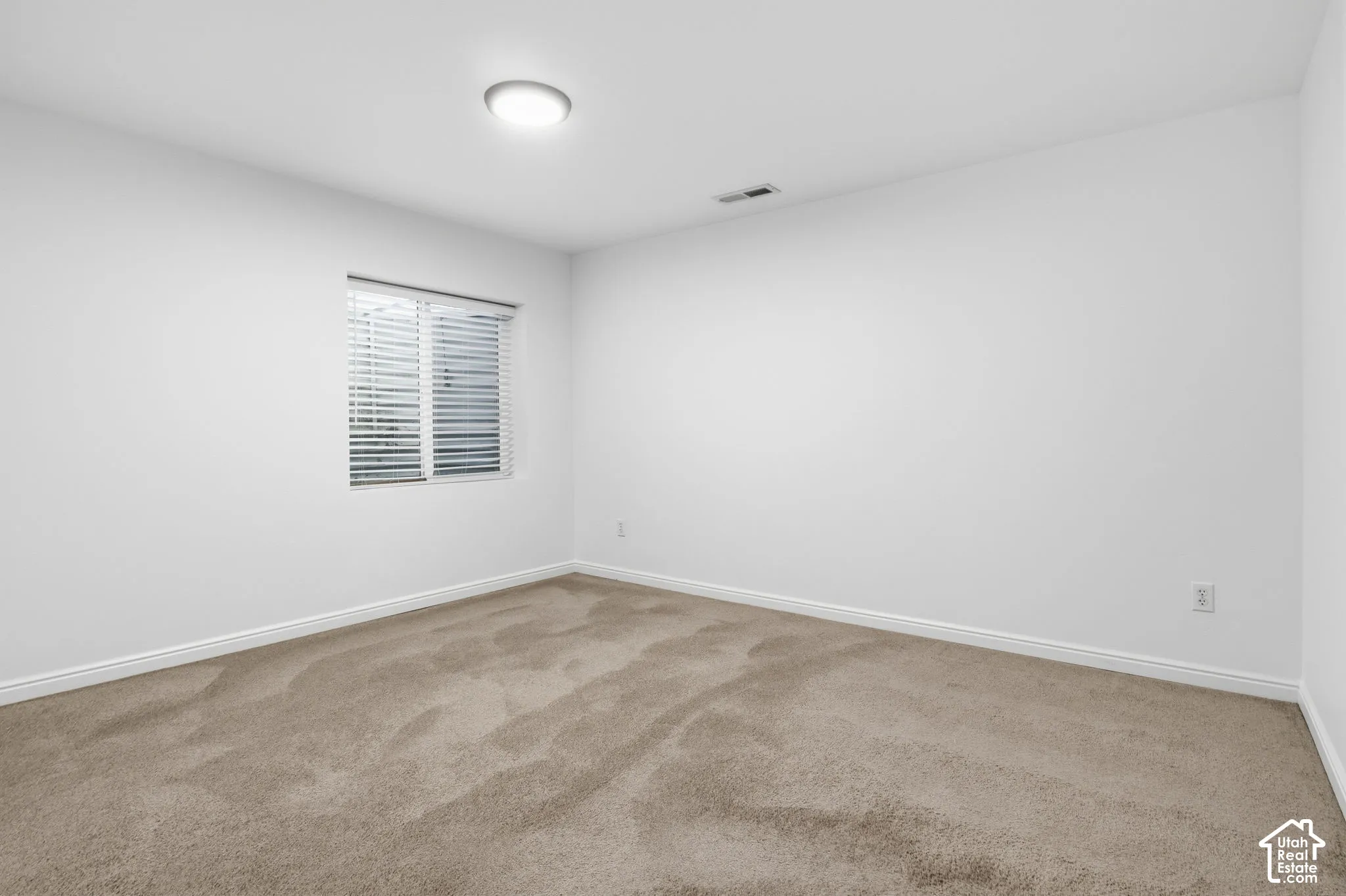 Neutral interior space featuring carpeted flooring, white walls, and a recessed ceiling light fixture
