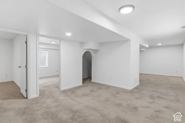 Neutral-toned carpeting, flush-mount lighting, and an arched architectural cutout featuring interior access