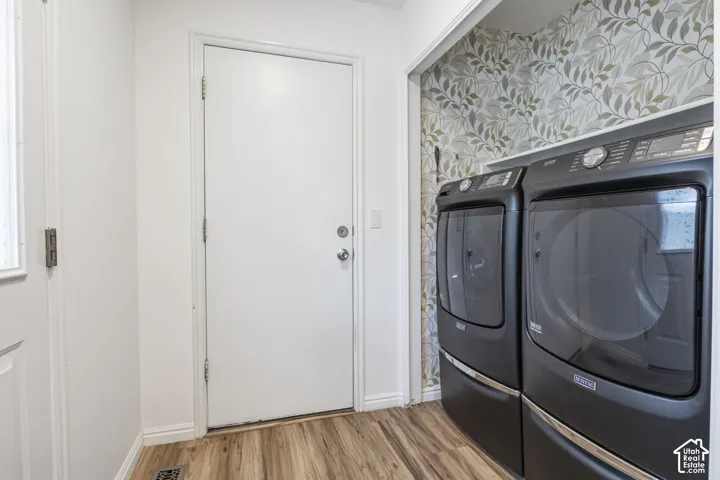 Laundry area featuring botanical-patterned wallpaper, built-in shelving, wood-finish flooring, and a dedicated exterior door