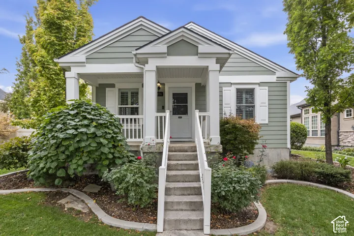 Exterior facade featuring horizontal siding, a covered front porch with square columns, white shutter accents, and a concrete staircase with railing