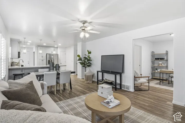 Open-concept interior featuring wood-finish flooring, recessed lighting, and a kitchen peninsula with shaker-style cabinetry and neutral countertops