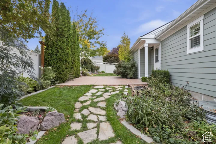 Backyard featuring a paved patio, flagstone pathway, mature columnar evergreens, and vinyl privacy fencing