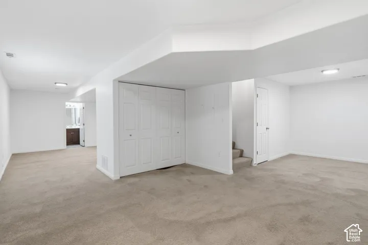 Open-concept area featuring neutral wall-to-wall carpeting, recessed ceiling lighting, and a white bi-fold closet