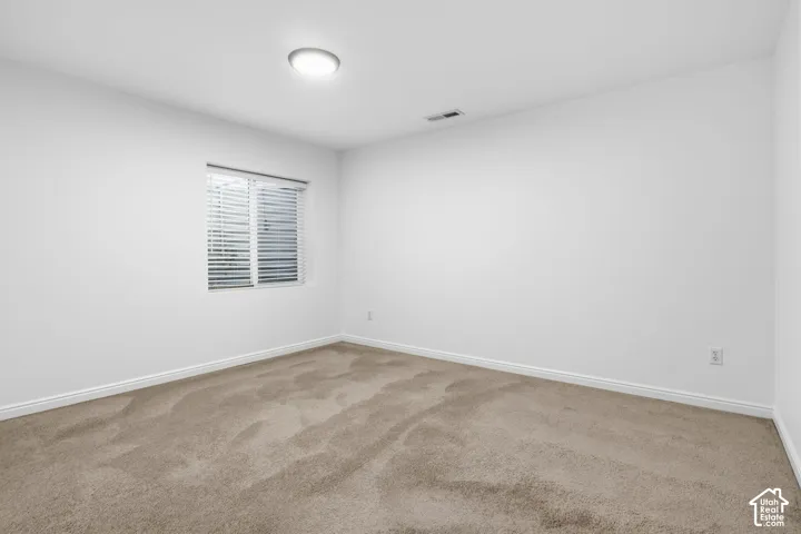Neutral interior space featuring carpeted flooring, white walls, and a recessed ceiling light fixture