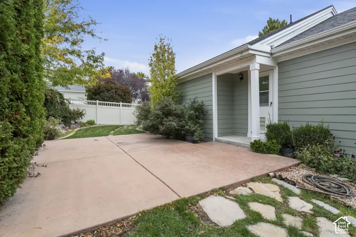 Exterior concrete patio featuring lap siding, white trim accents, a stone-path walkway, and perimeter privacy fencing