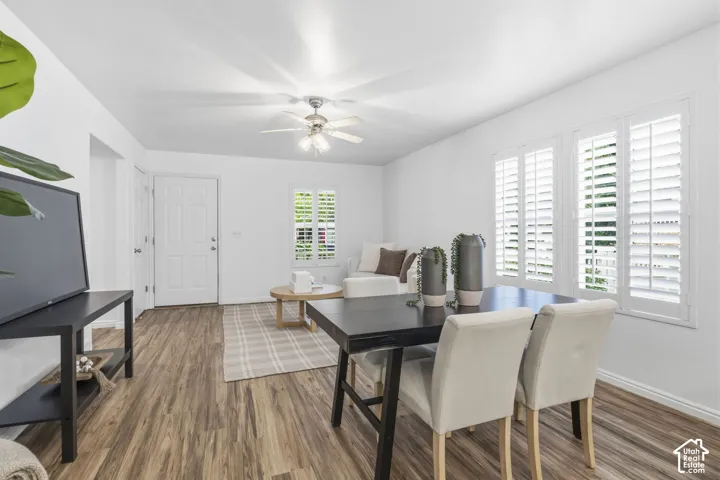 Open floor plan featuring wood-finish flooring, white plantation shutters, and a central ceiling fan with integrated lighting