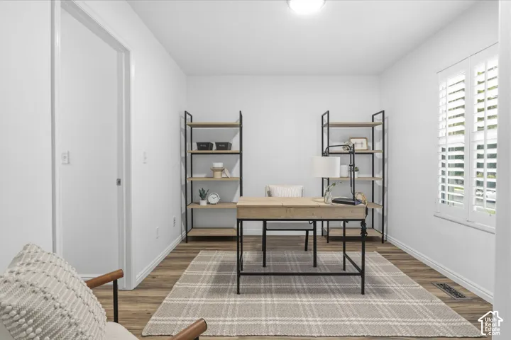 Interior room featuring wood-finish flooring, white walls, and interior window shutters