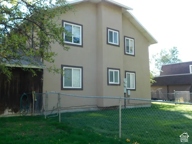 Stucco exterior featuring multi-level construction, dark-trimmed window casings, and a fenced-in yard area