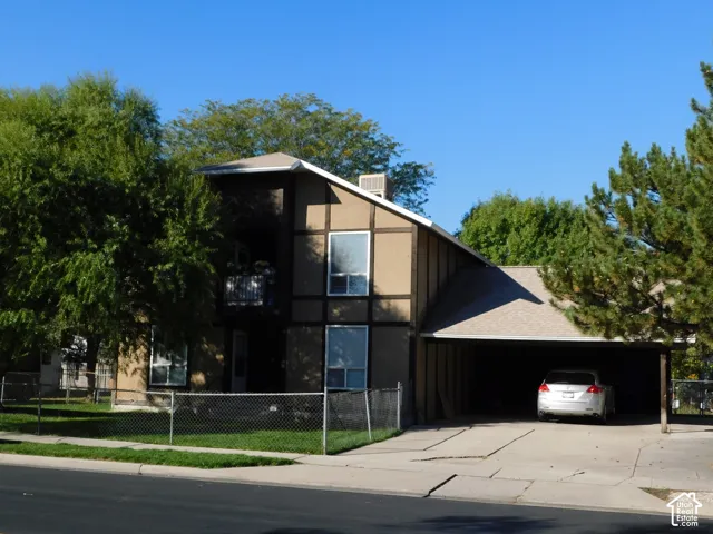 Multi-story exterior with half-timbering details, shingle roof, second-level balcony, and attached covered parking structure