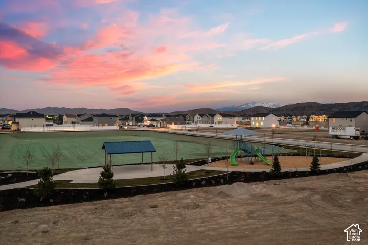 Community park featuring a pavilion, play structure, manicured lawn, and mountain backdrop