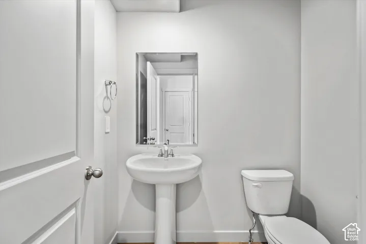 Powder room featuring a white pedestal sink, chrome faucet, wall-mounted mirror, and a circular towel ring