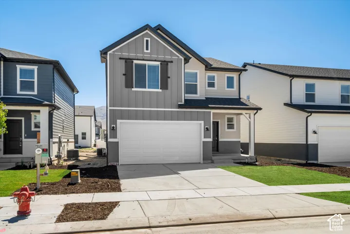 Two-story exterior featuring vertical siding, board and batten detailing, decorative exterior shutter, attached two-car garage, and a concrete driveway