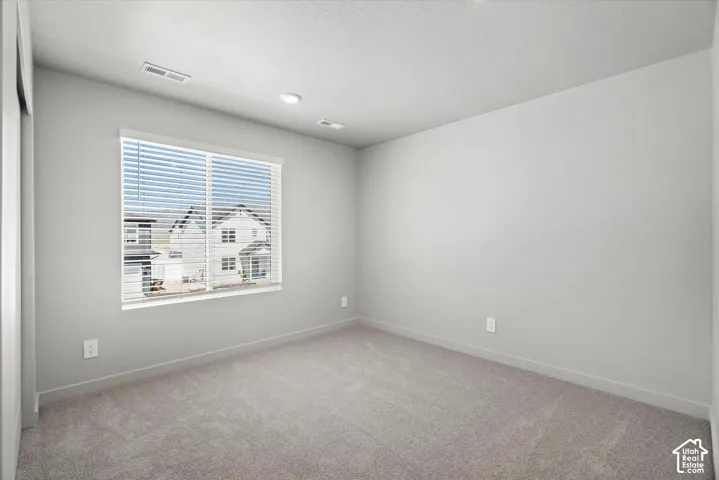 Neutral-toned interior space featuring light-colored wall paint, plush carpeting, and recessed ceiling lighting