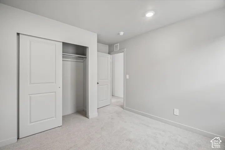 Neutral-toned interior featuring wall-to-wall carpeting, recessed ceiling lighting, and a closet with a sliding panel door