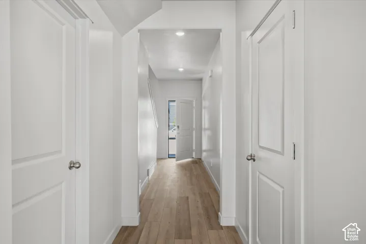 Hallway featuring wood-finish flooring, recessed lighting, and crisp white panel doors