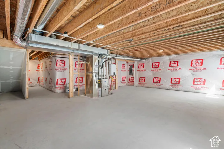 Unfinished basement featuring exposed wood joists, concrete flooring, vapor-barrier foundation walls, and a dedicated HVAC utility system