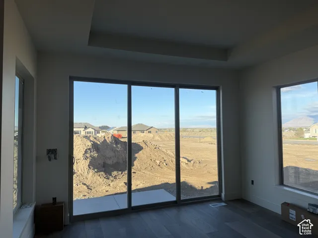 Tray ceiling, wood-finish flooring, and large multi-panel sliding glass doors with direct exterior access