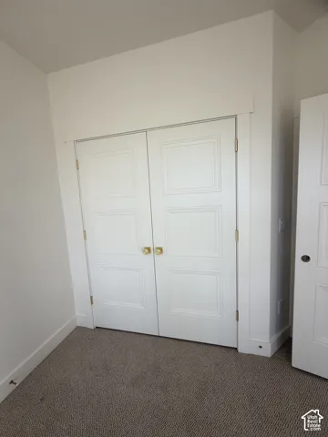 White double-door closet featuring a recessed three-panel design, traditional casing, and brass-finish hardware