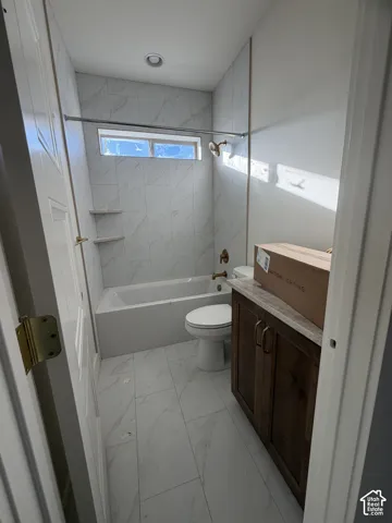 Bathroom featuring stone-finish wall and floor tile, built-in tub with integrated shelving, dark wood-finish cabinetry, and metallic fixtures