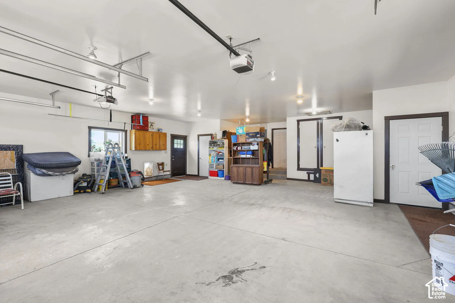 Spacious multi-car garage featuring a smooth concrete floor, recessed lighting, and built-in wood cabinetry